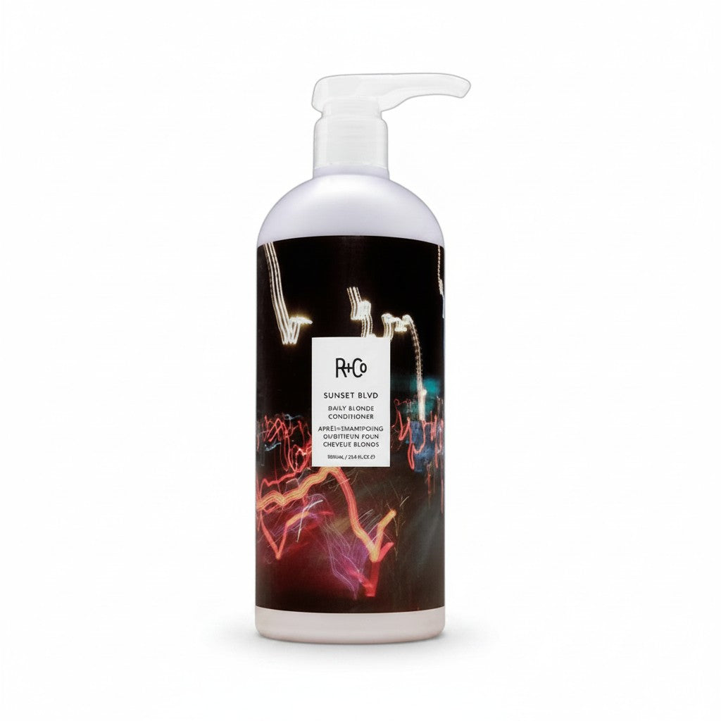 A bottle of H2O Sunset Blvd Deep Shampoo on a clean white background. The bottle is white with a clear pump dispenser and features a black label with a colorful light streak graphic.